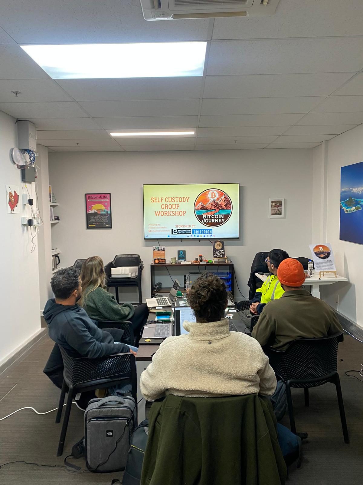 Attendees sitting at laptops facing a screen headed "Self custody group workshop".
